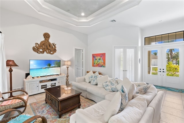 living room featuring a raised ceiling, light tile patterned floors, french doors, ornamental molding, and a high ceiling