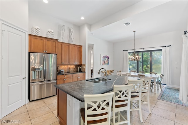 kitchen featuring pendant lighting, a chandelier, sink, stainless steel fridge with ice dispenser, and a breakfast bar area