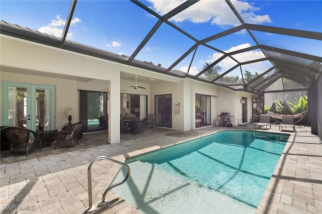 view of pool featuring glass enclosure, a patio area, and ceiling fan