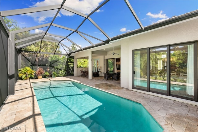 view of swimming pool featuring glass enclosure, ceiling fan, and a patio