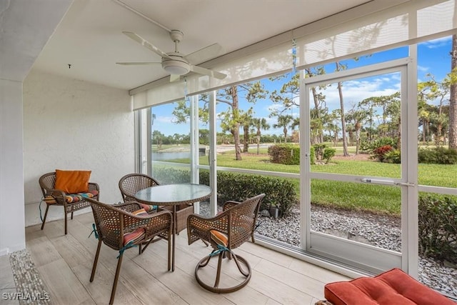 sunroom / solarium featuring ceiling fan and a water view