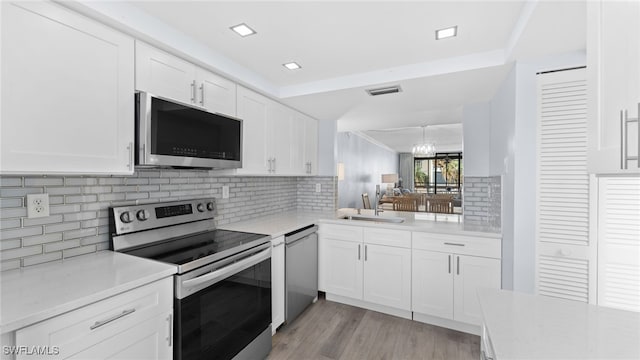 kitchen featuring stainless steel appliances, sink, a notable chandelier, light hardwood / wood-style floors, and white cabinetry