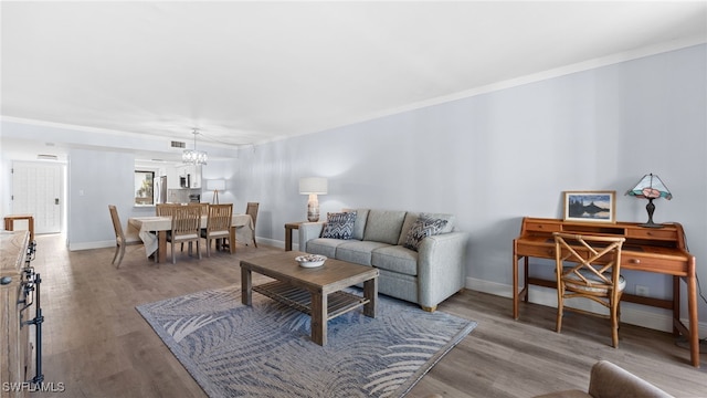 living room featuring hardwood / wood-style floors, ornamental molding, and a notable chandelier