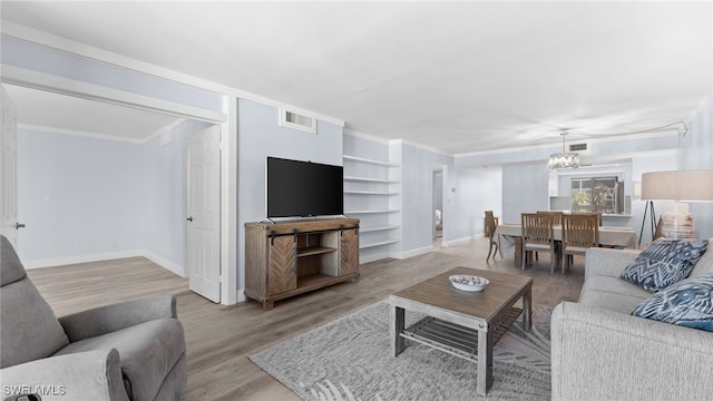 living room featuring light hardwood / wood-style flooring, a chandelier, and ornamental molding