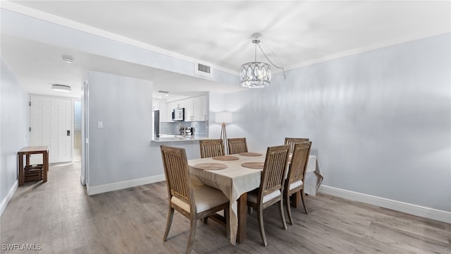 dining area featuring light hardwood / wood-style floors and a chandelier