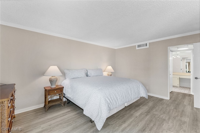 bedroom with ornamental molding, ensuite bathroom, and light hardwood / wood-style floors