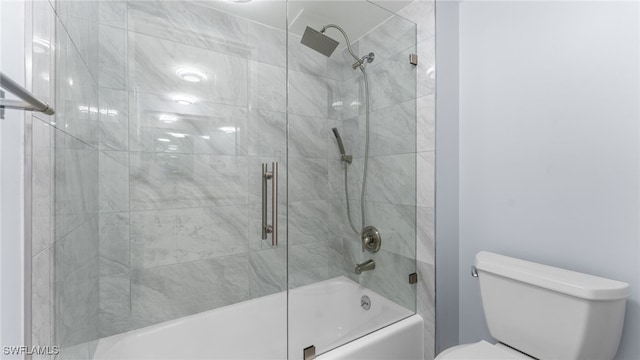 bathroom featuring toilet and shower / bath combination with glass door