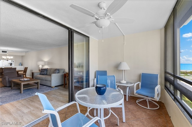 sunroom / solarium featuring ceiling fan with notable chandelier