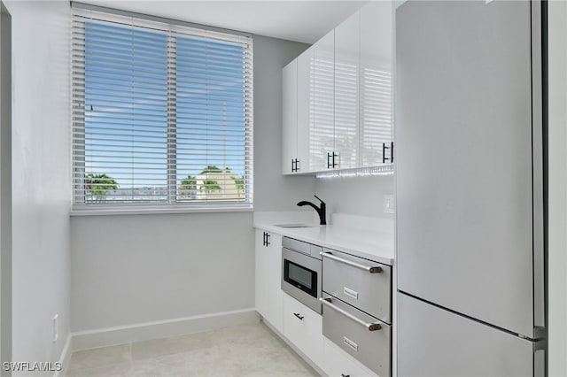 kitchen featuring stainless steel microwave, white cabinets, white fridge, and sink