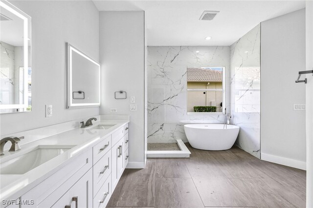 bathroom with vanity, plus walk in shower, and a healthy amount of sunlight