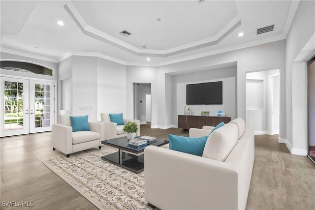 living room with french doors, ornamental molding, and a raised ceiling