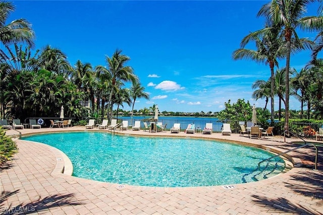 view of swimming pool featuring a water view and a patio