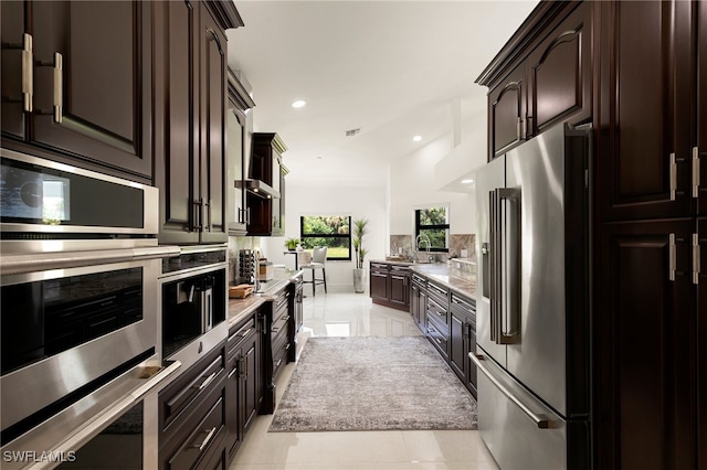 kitchen featuring dark brown cabinets, light tile patterned floors, and high end refrigerator