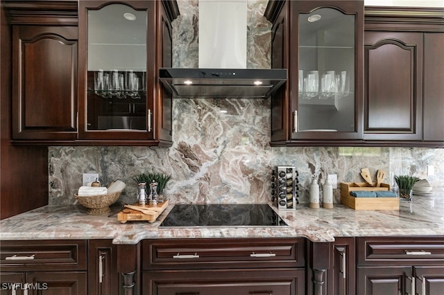 bar with dark brown cabinets, wall chimney exhaust hood, and black electric stovetop