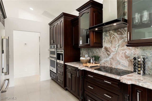 kitchen featuring vaulted ceiling, light stone counters, tasteful backsplash, black electric stovetop, and wall chimney range hood