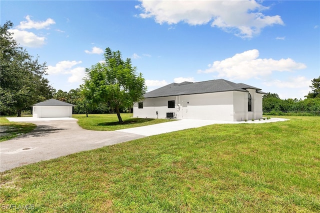 view of front of house featuring a garage, a front lawn, and an outbuilding