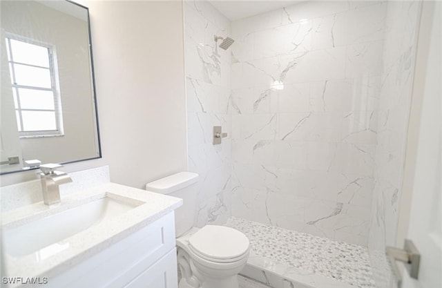 bathroom featuring tiled shower, toilet, and vanity