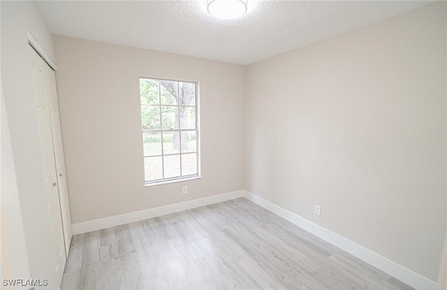 unfurnished bedroom featuring a closet, a textured ceiling, and light hardwood / wood-style flooring