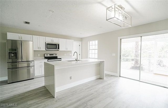 kitchen featuring a kitchen island with sink, light wood-type flooring, sink, appliances with stainless steel finishes, and white cabinets