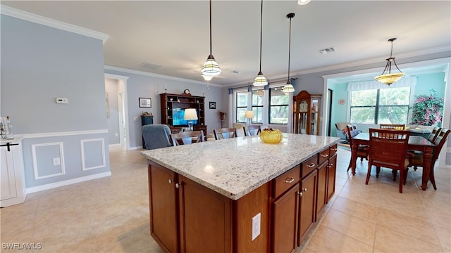 kitchen with ornamental molding, decorative light fixtures, light stone countertops, and a kitchen island