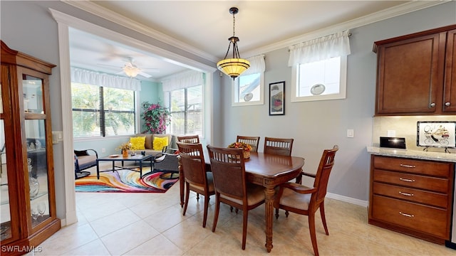 dining area featuring light tile patterned floors, a ceiling fan, crown molding, and baseboards