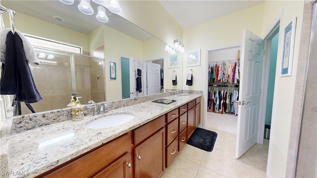 bathroom with a shower stall, a walk in closet, double vanity, tile patterned floors, and a sink