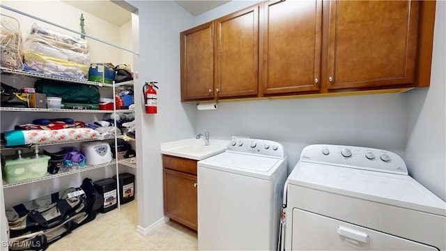 laundry area featuring a sink, cabinet space, light tile patterned floors, and washer and clothes dryer