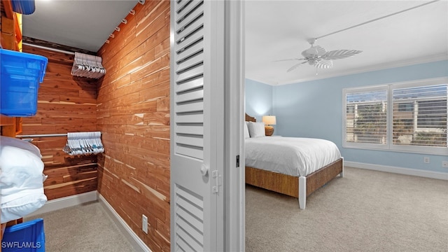 carpeted bedroom with crown molding, wood walls, and ceiling fan