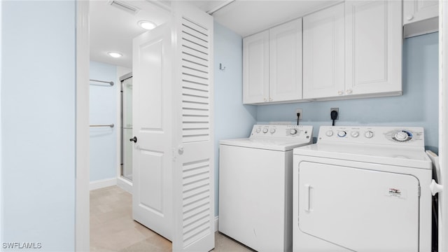 clothes washing area with washing machine and clothes dryer and cabinets