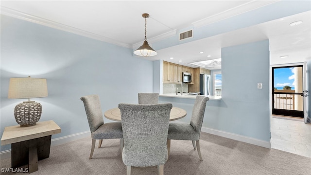 dining room with crown molding and light colored carpet