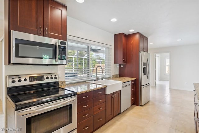 kitchen with a sink, recessed lighting, stainless steel appliances, baseboards, and light stone countertops