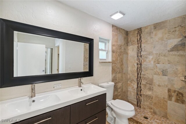 bathroom with tiled shower, toilet, a textured ceiling, and vanity