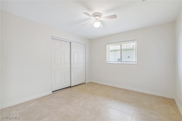 unfurnished bedroom featuring a closet, light tile patterned floors, ceiling fan, and baseboards