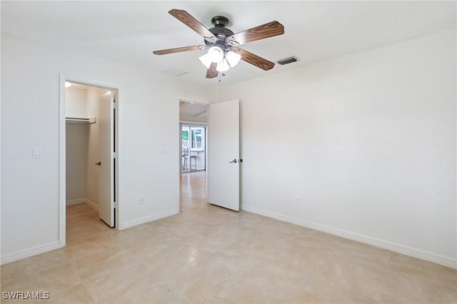 unfurnished bedroom featuring visible vents, a walk in closet, ceiling fan, baseboards, and a closet