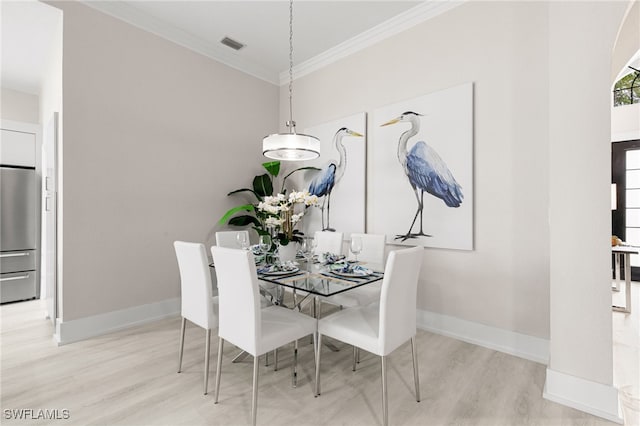 dining room with crown molding and light wood-type flooring