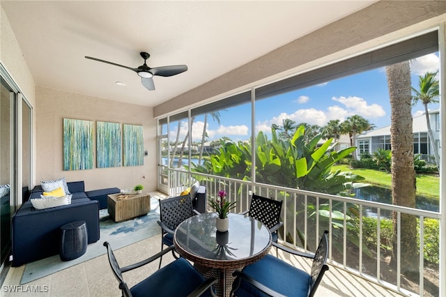 sunroom featuring a water view and ceiling fan