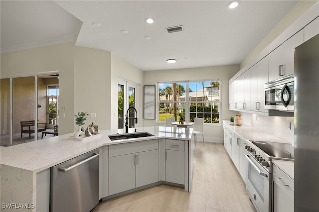 kitchen with appliances with stainless steel finishes, sink, a center island with sink, and white cabinets