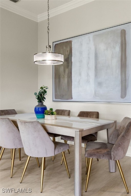 dining space featuring crown molding and light hardwood / wood-style floors