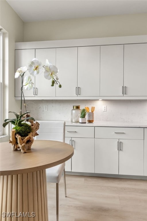 kitchen featuring white cabinetry, decorative backsplash, and light wood-type flooring