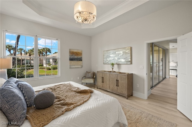 bedroom featuring a chandelier, a raised ceiling, and light wood-type flooring