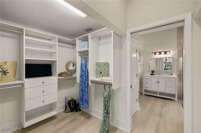 walk in closet with light hardwood / wood-style flooring