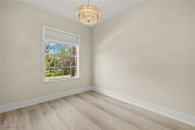 unfurnished room featuring an inviting chandelier and light hardwood / wood-style floors