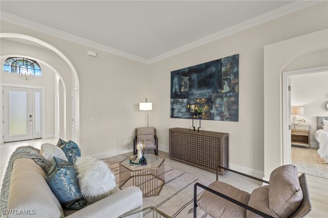 living room featuring crown molding, an inviting chandelier, and light wood-type flooring