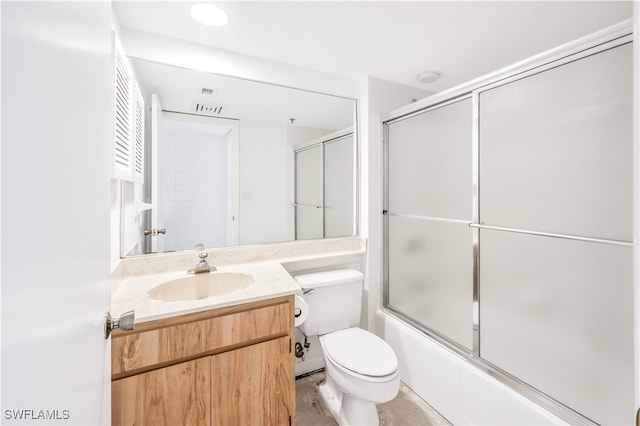 full bathroom featuring combined bath / shower with glass door, vanity, and toilet