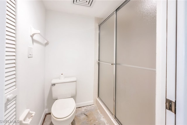 bathroom featuring a shower with door and toilet