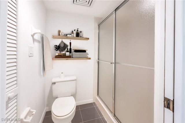 bathroom featuring toilet, an enclosed shower, and tile patterned floors