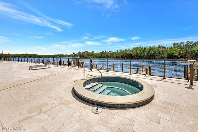 view of pool featuring a water view, a patio area, and an in ground hot tub