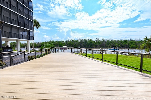 wooden terrace featuring a water view and a lawn