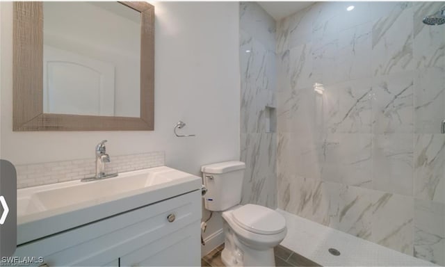 bathroom featuring vanity, a tile shower, and toilet