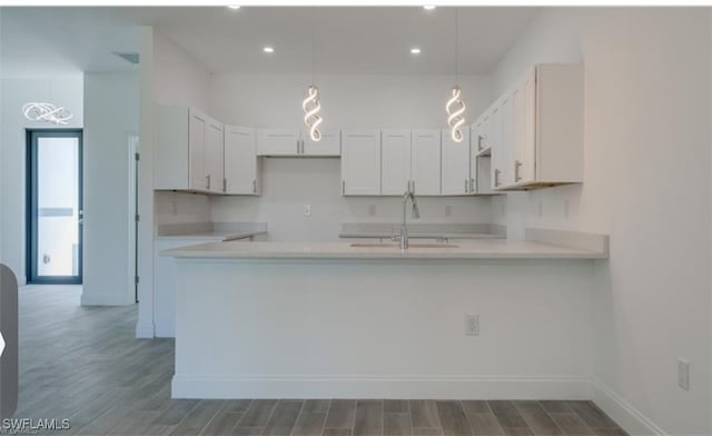 kitchen with hardwood / wood-style flooring, decorative light fixtures, sink, and white cabinetry